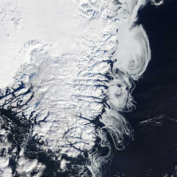 Satellite image of Greenland’s southern coast, captured on February 24, 2025, showing the snow-covered ice sheet, glaciers, and swirling sea ice patterns along the North Atlantic Ocean. The image, taken by NASA’s Terra satellite using the MODIS sensor, highlights seasonal snow cover, patchy clouds, and the interaction between sea ice and ocean currents.